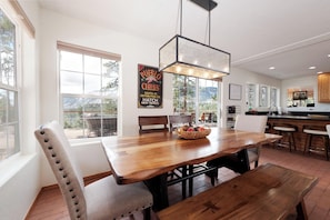 A dining area with a wooden table, chairs, and a hanging light fixture. - Luxury Home - Huge Deck - Great Views - Hot Tub/Fire Table - 2 Miles to Purg (Durango)