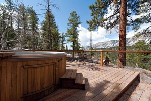 A wooden deck with a hot tub, wooden benches, and a view of mountains and trees. - Luxury Home - Huge Deck - Great Views - Hot Tub/Fire Table - 2 Miles to Purg (Durango)