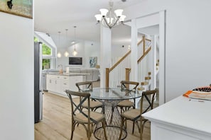 A modern kitchen with a dining area, white cabinetry, and a chandelier.