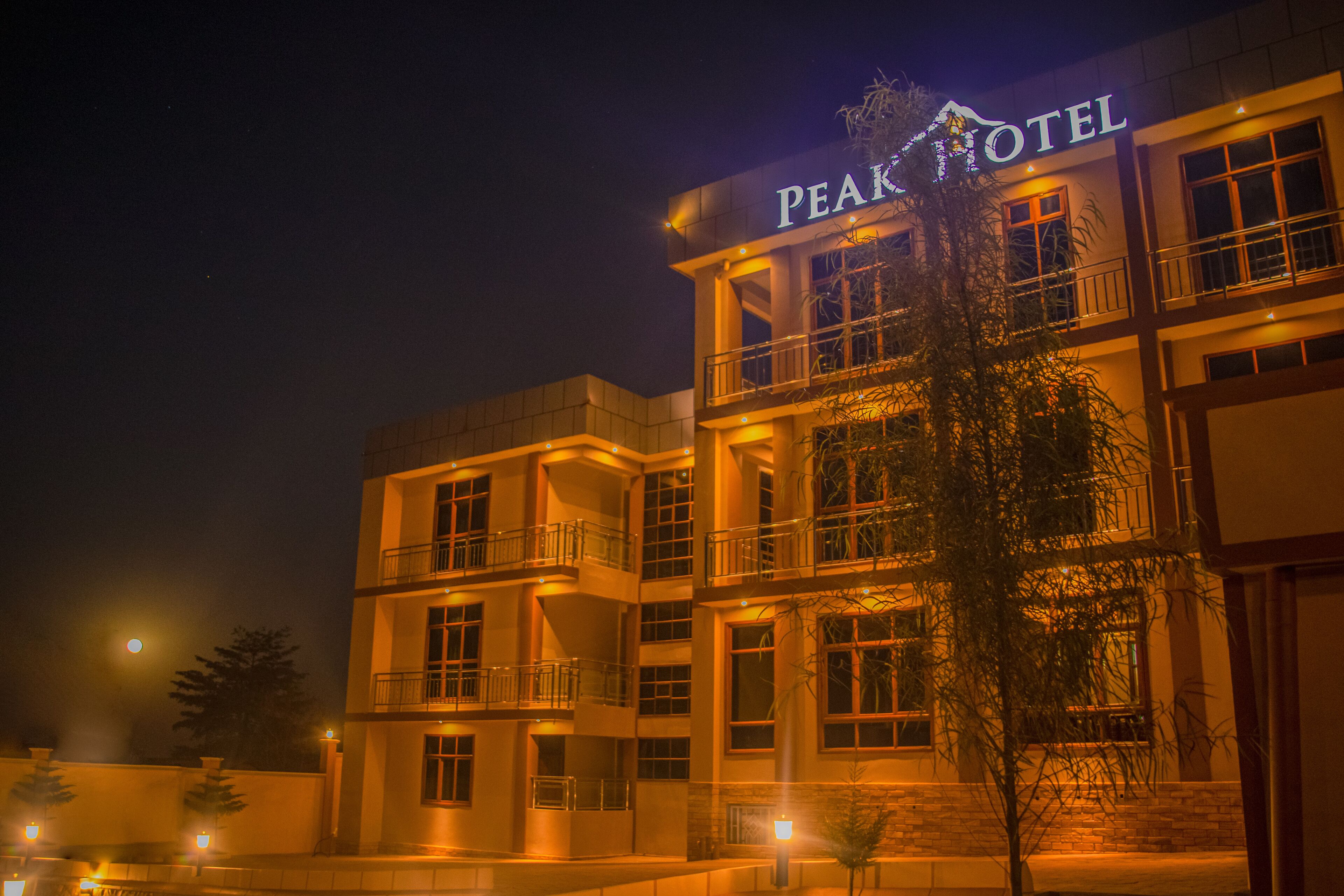 Un hotel de varios pisos con balcones y un letrero que dice "PEAK HOTEL".