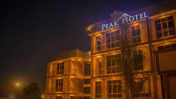 Un hotel de varios pisos con balcones y un letrero que dice "PEAK HOTEL".