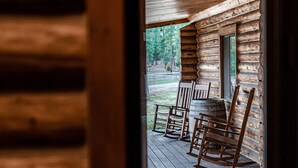 Eine Holzhütte mit Veranda, Schaukelstühlen und Blick auf den umliegenden Wald.