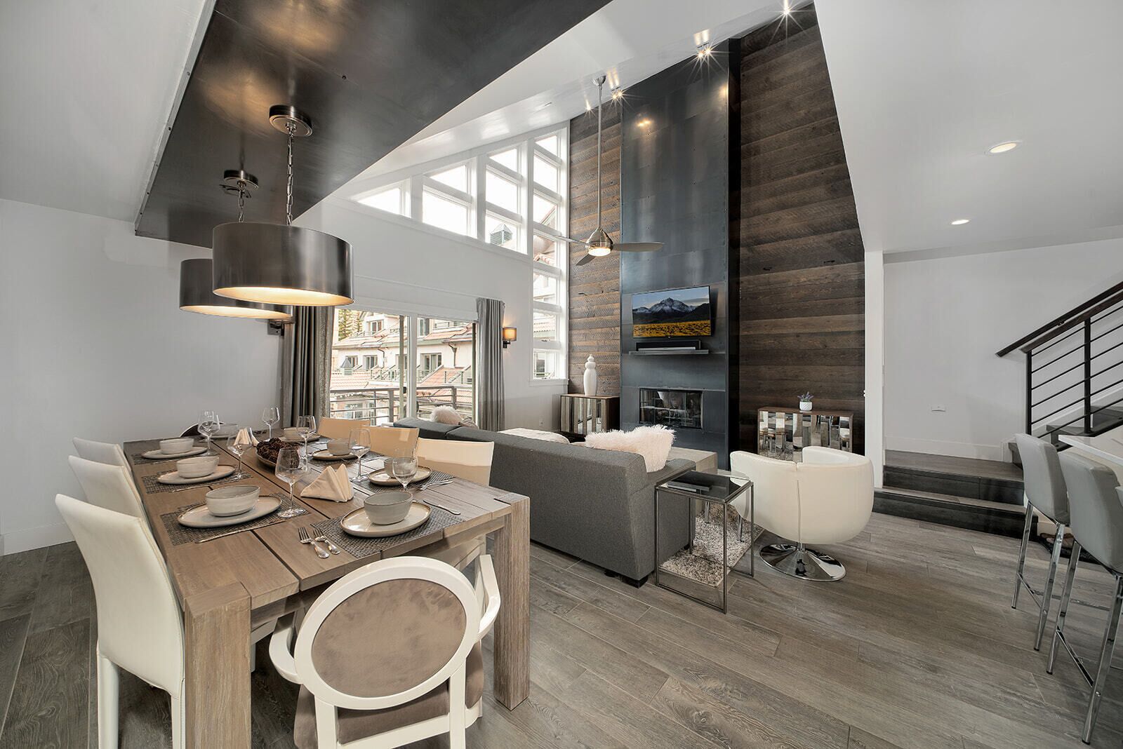 A modern dining area with a wooden table set for six, a sofa, and a fireplace.