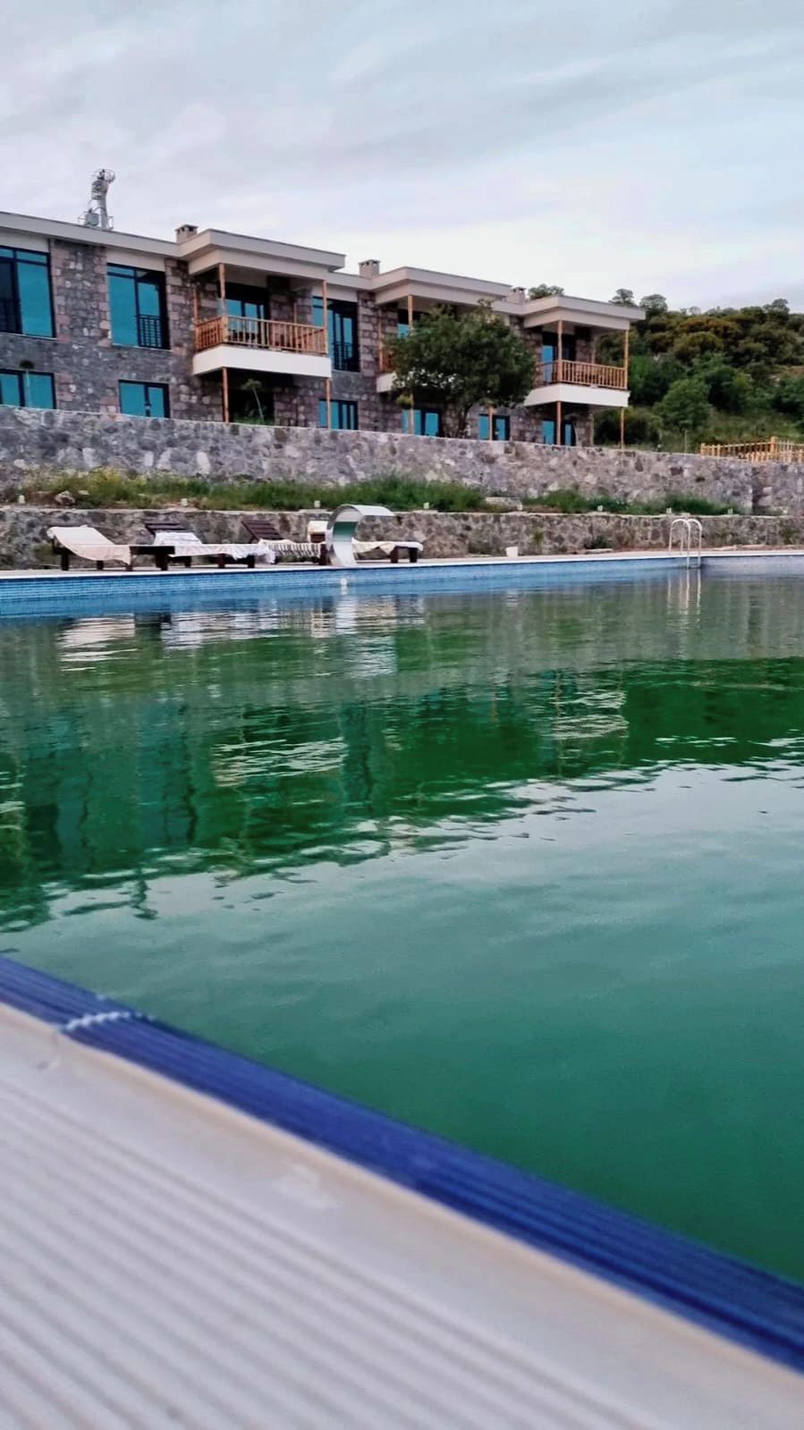 A swimming pool with lounge chairs and a stone wall.
