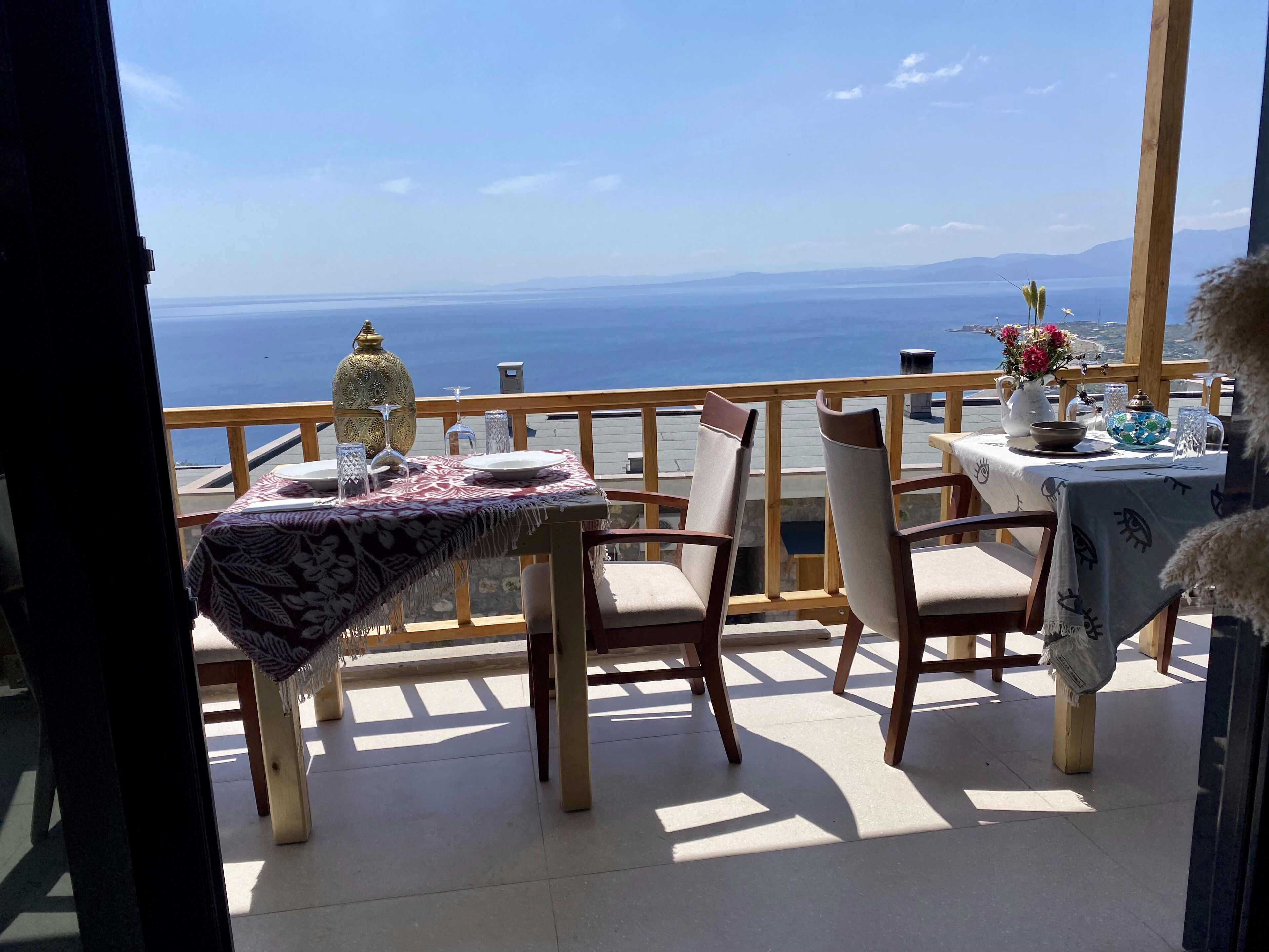 A balcony with a table set for two, overlooking a scenic view of the sea.