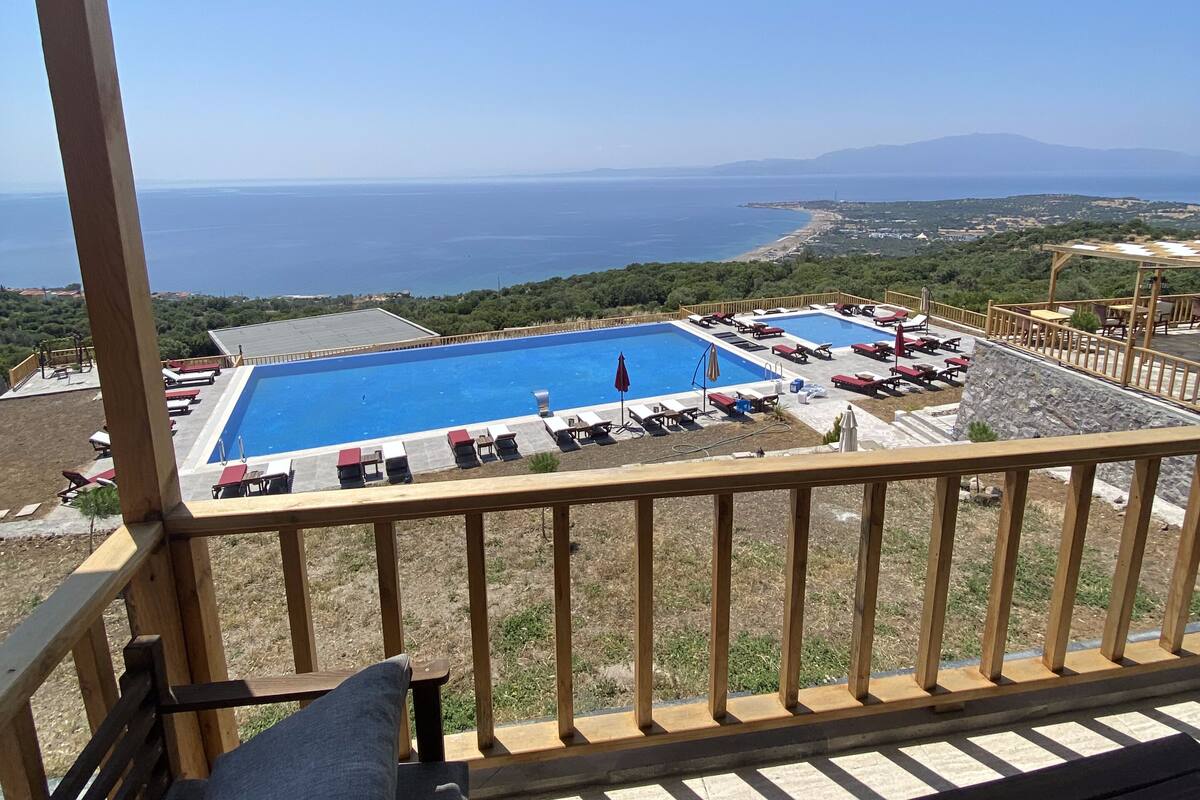 A balcony with a view of a swimming pool and the sea.