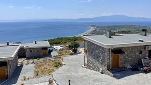 A stone building with a view of the sea and mountains. - Assos Karadut Taş Otel (Ayvacik)