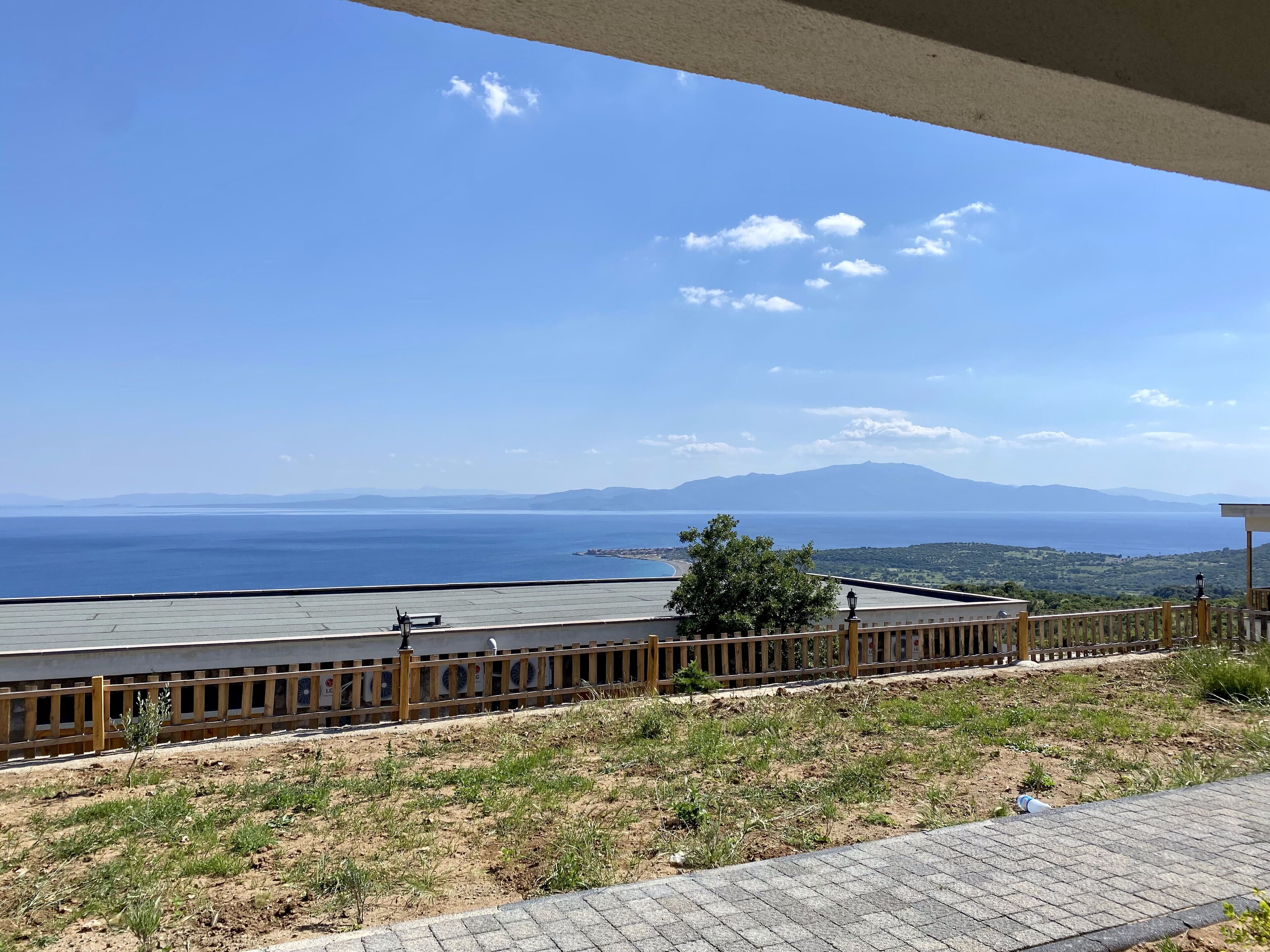 A terrace with a view of the sea and distant mountains.