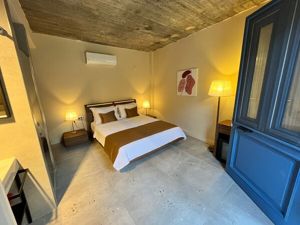 Un dormitorio con una cama, lámparas de noche, aire acondicionado de pared y una puerta.