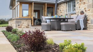 A stone house with a covered patio, outdoor seating, and a garden. - Trevilges Cottage (Helston)