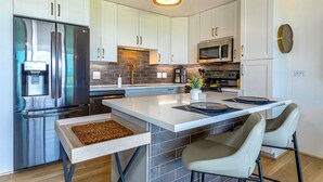 A modern kitchen with stainless steel appliances, white cabinetry, and a central island with seating.