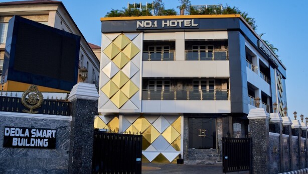 A modern hotel with a geometric facade, a prominent entrance gate, and a sign for the Deola Smart Building. - No.1 Hotel Ibadan (Ibadan)