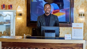 A hotel reception desk with a television displaying National Geographic, a 'Dear Guest' sign, and a 'No Smoking' sign. - No.1 Hotel Ibadan (Ibadan)