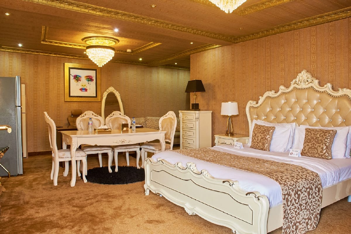 Um quarto luxuoso com uma cama grande, uma penteadeira com espelho, uma escrivaninha e um candelabro.