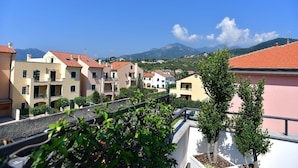 A residential area with multi-story buildings, balconies, and a mountainous backdrop.