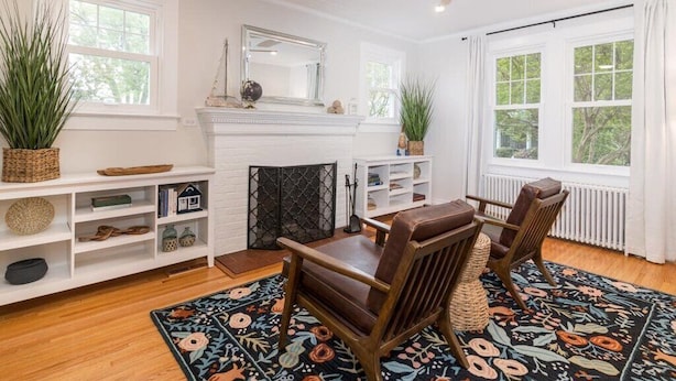 A living room with a fireplace, wooden furniture, and a patterned rug. - Minutes from Downtown St. Michaels and Tilghman | Private Dock | Outdoor Dining (Sherwood)