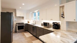 A modern kitchen with white cabinets, a stainless steel refrigerator, an oven, a microwave, and a coffee maker. - Minutes from Downtown St. Michaels and Tilghman | Private Dock | Outdoor Dining (Sherwood)