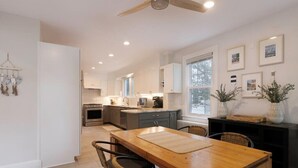 A modern kitchen with a wooden dining table, dark cabinetry, and pendant lights. - Minutes from Downtown St. Michaels and Tilghman | Private Dock | Outdoor Dining (Sherwood)