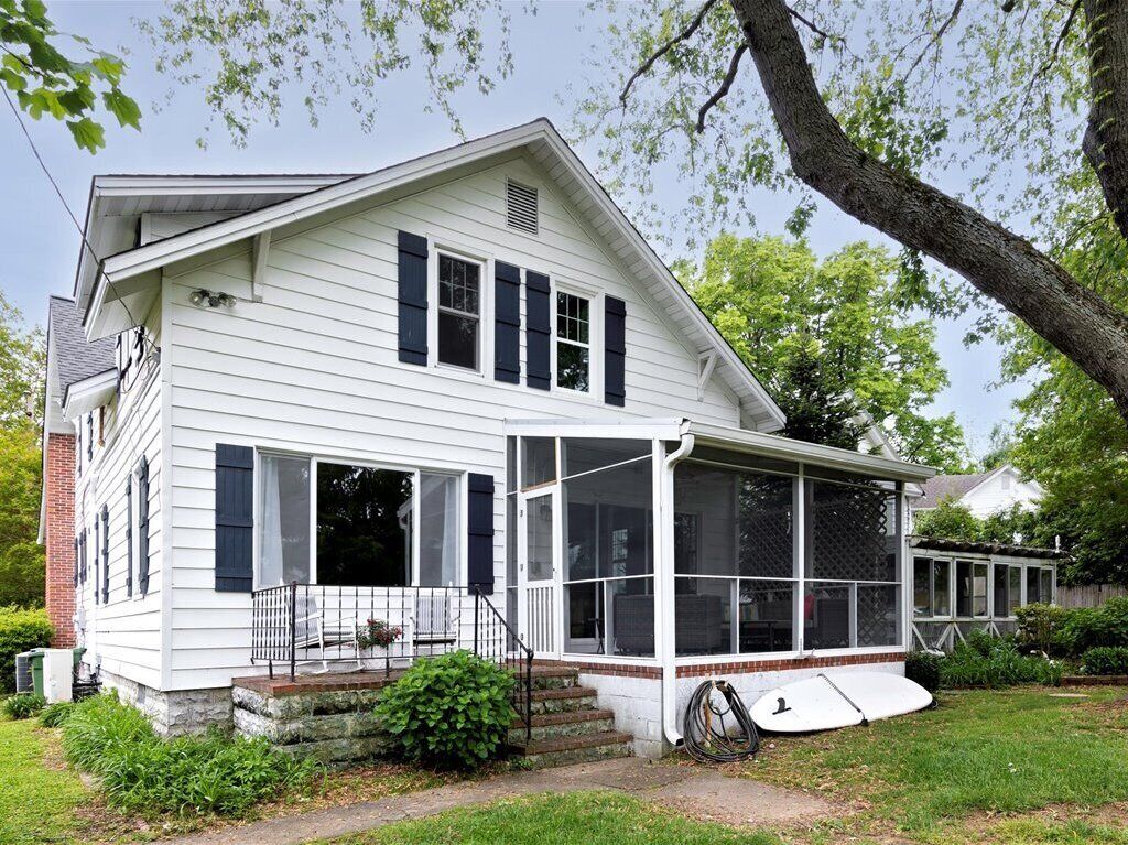 A white two-story house with a covered porch and a large windowed front area.