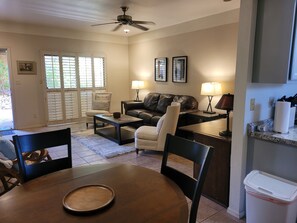 A living room with a sofa, coffee table, and chairs, a dining area with a table and chairs, and a kitchen area with a countertop and appliances. - Relaxing condo with easy access to the pool-shopping-restaurants in Foothills (Tucson)