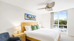 Une chambre d’hôtel avec un lit, une table de chevet, une chaise, un ventilateur de plafond et une fenêtre donnant sur un paysage agréable.
