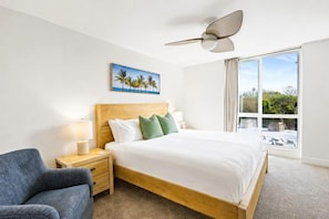 A hotel room with a bed, a nightstand, a chair, a ceiling fan, and a window with a view. - Ocean-View Condo at North Coast Village | B222 (Oceanside)