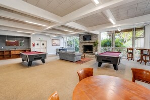 Une salle de billard équipée de deux tables de billard, d’un canapé et d’une cheminée.