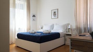 A neatly arranged bedroom with a bed, bedside tables, a desk, and a chair.