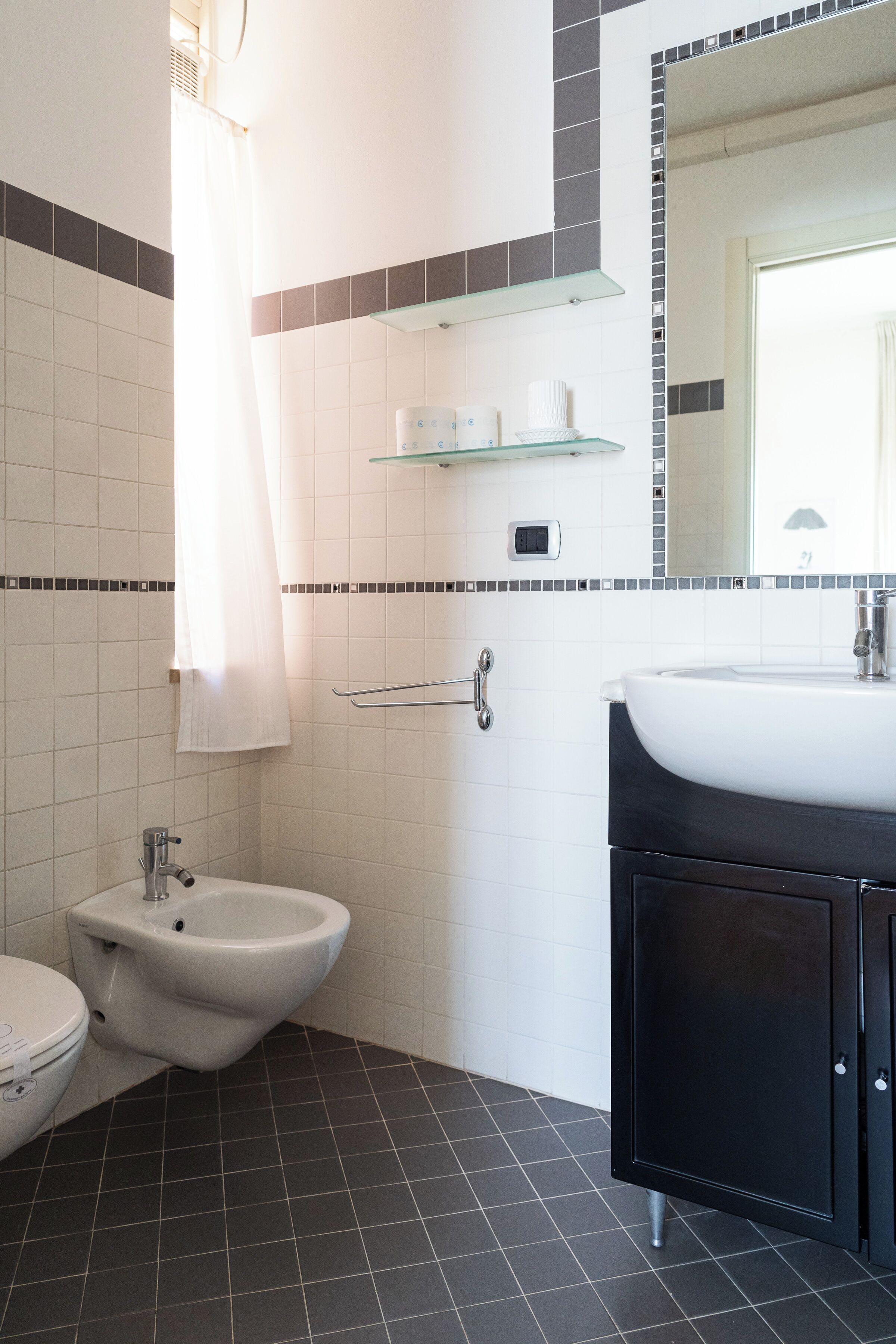 A bathroom with a bidet, a toilet, a sink, and a mirror.