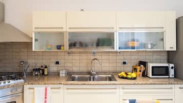 A kitchen with a stainless steel sink, a microwave, and a stove.