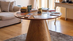Een woonkamer met een ronde houten salontafel, een bank, een lamp en een kroonluchter.
