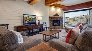 Una sala de estar con chimenea, televisión y vista al exterior.