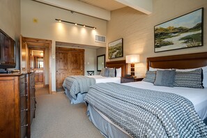 Habitación de hotel con dos camas, un aparador de madera, un cuadro grande y un espejo.
