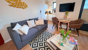 Een moderne woonkamer met een grijze bank, een salontafel en een televisie.