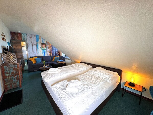 Une chambre confortable située dans les combles, avec un grand lit, un canapé et une petite table avec une lampe.