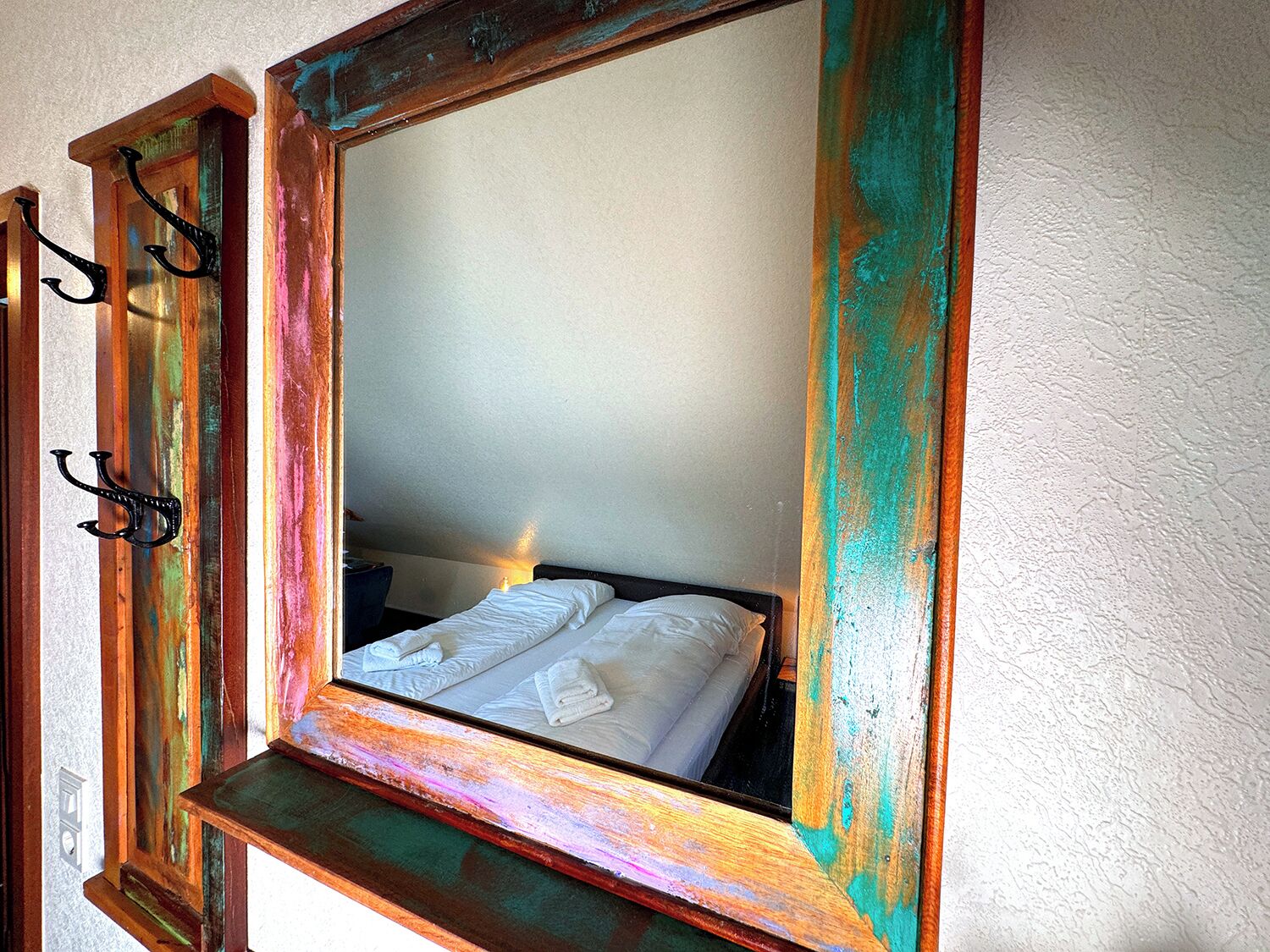 Ein Zimmer mit einem Bett, einem Spiegel und einem Wandhaken.