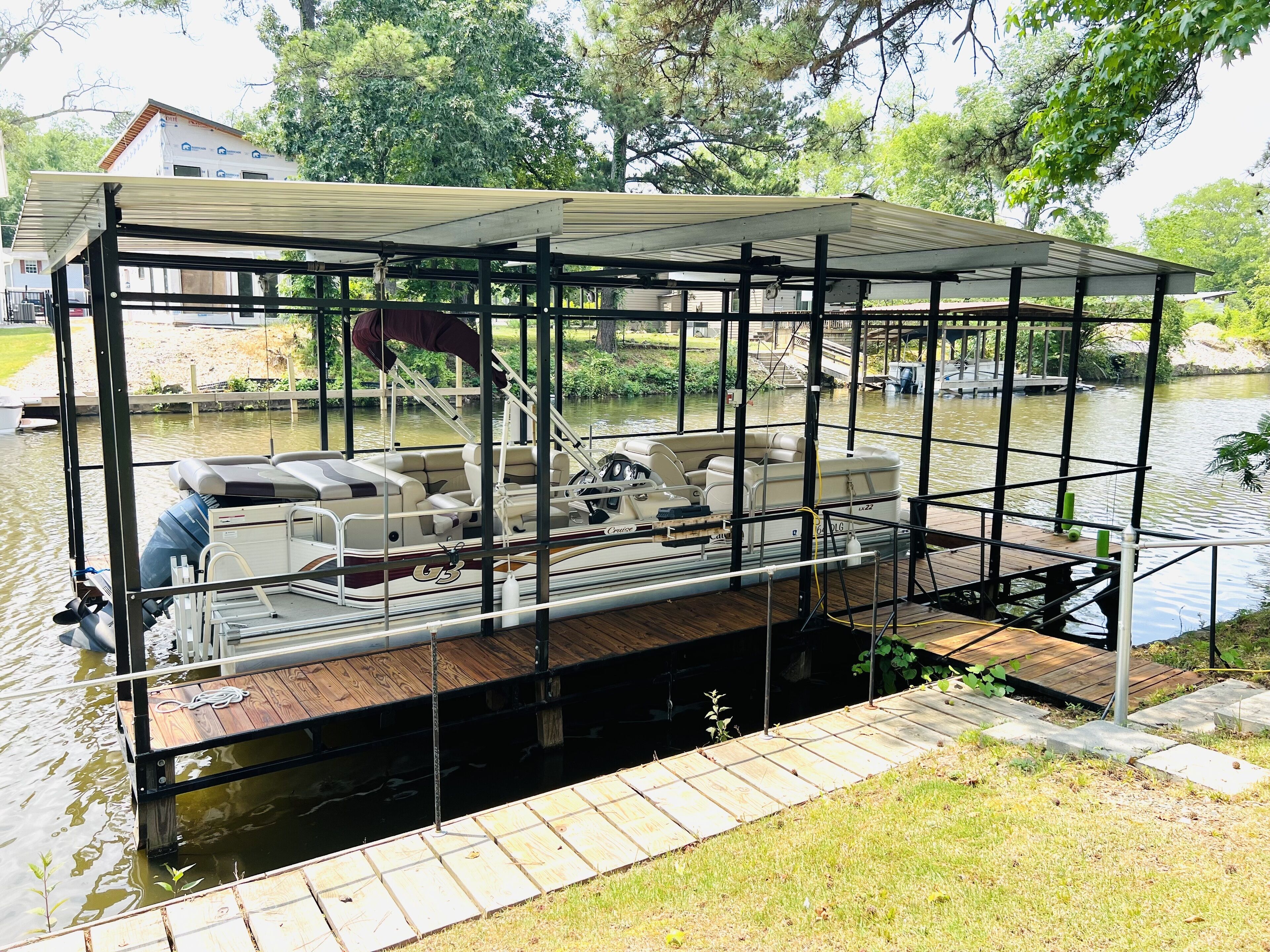 A covered boat dock with a wooden deck, a steering wheel, and a seating area.