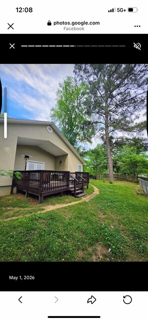 A residential property with a fenced yard, a pathway, and a large tree.