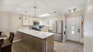 Una cocina moderna con una isla grande, electrodomésticos de acero inoxidable y una zona de comedor con mesa y sillas.