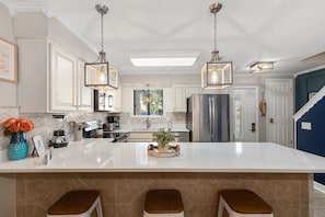A modern kitchen with a large island, stainless steel appliances, and pendant lighting.