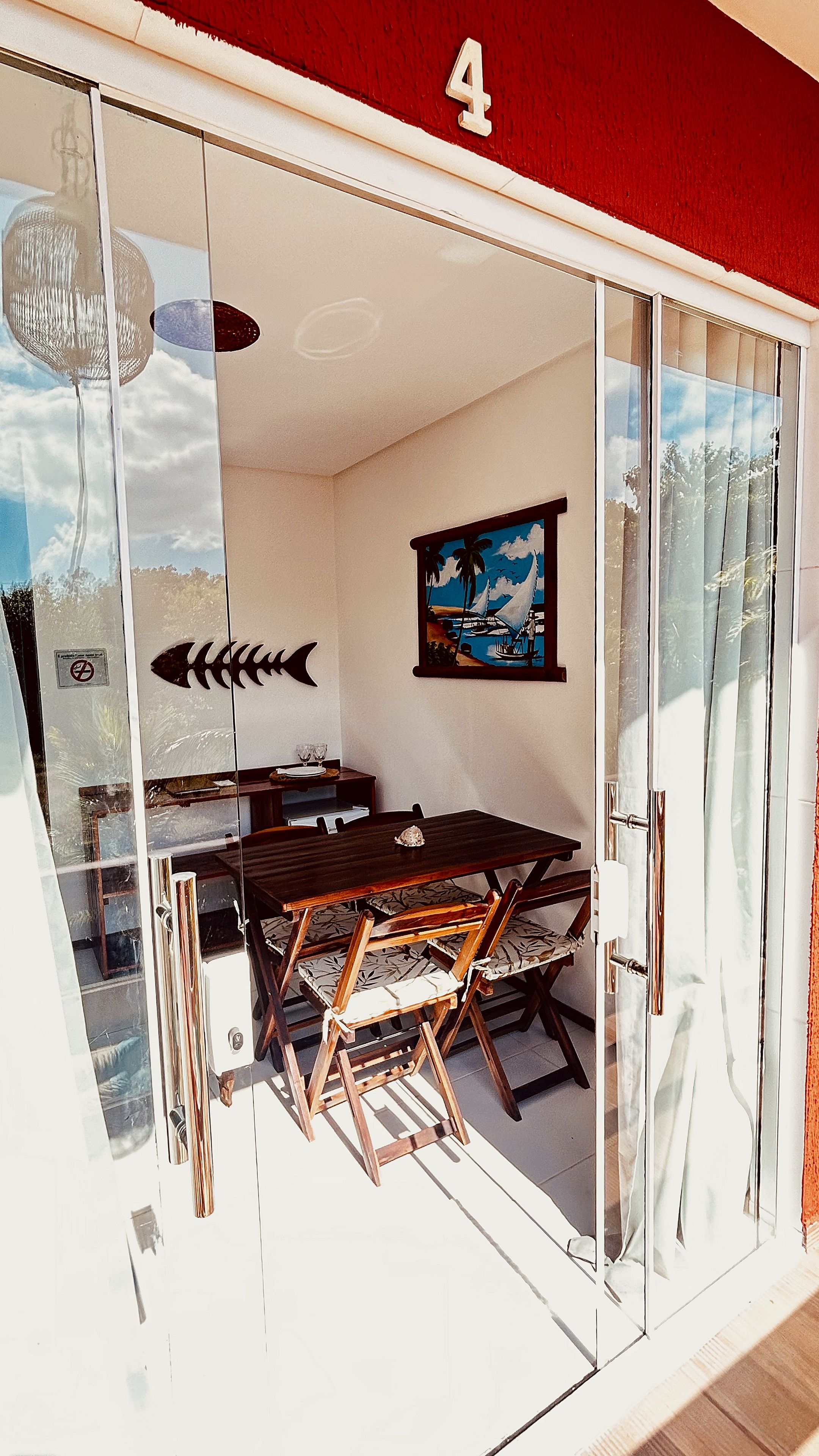 A room with a dining table, chairs, a framed picture, and a glass door with a number '4' above it.