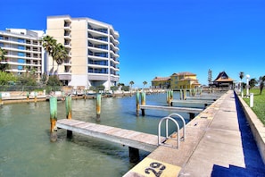 Un hotel frente al agua con varios balcones, un muelle y vista despejada del agua.