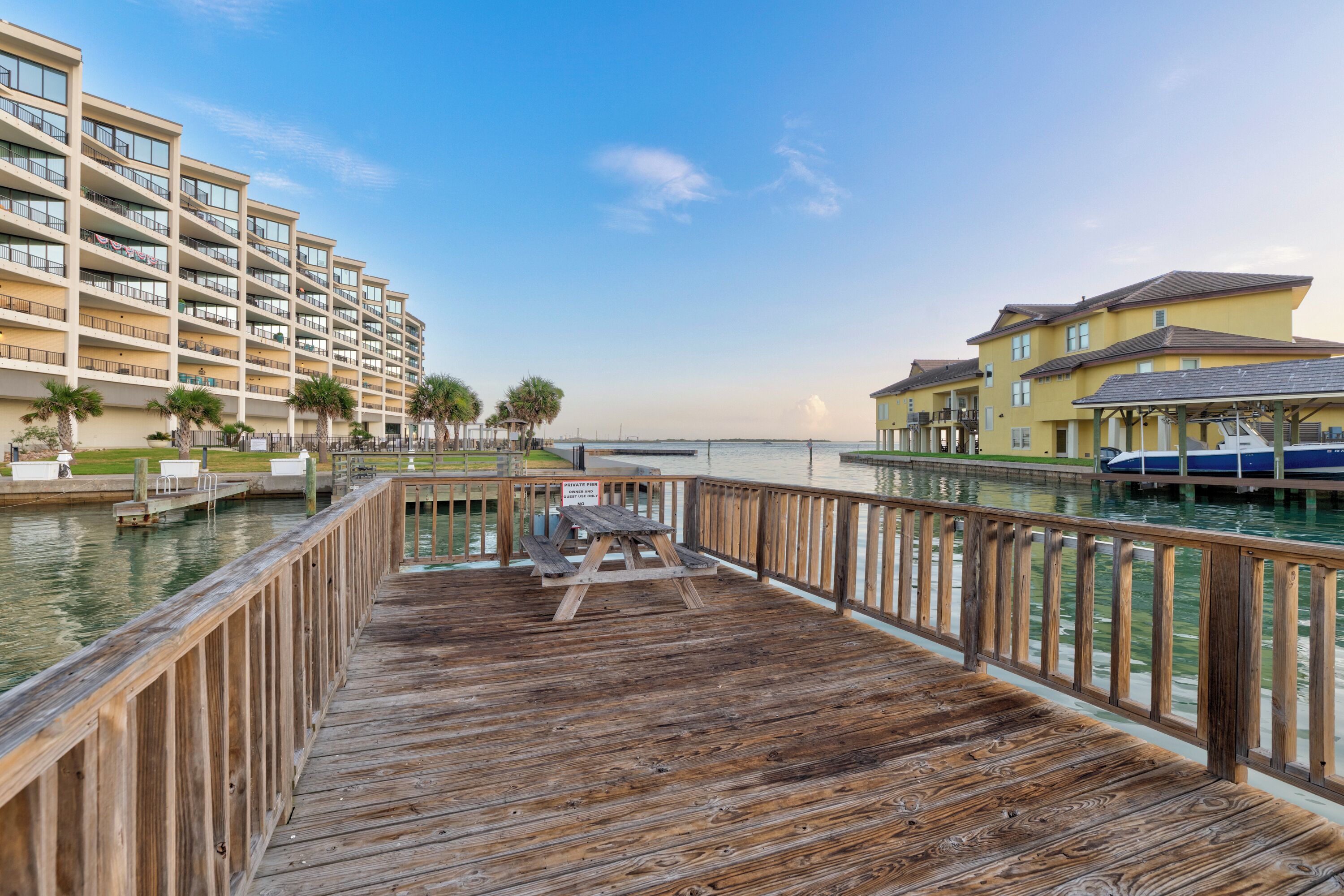 A wooden deck with a pool, a boat dock, and a building with balconies.
