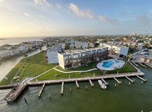 Vista aérea de una zona residencial costera con un puerto deportivo, una piscina y un edificio grande con varios balcones.