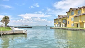 Una proprietà sul lungomare con un molo, un edificio giallo con balconi e vista chiara sull'acqua.
