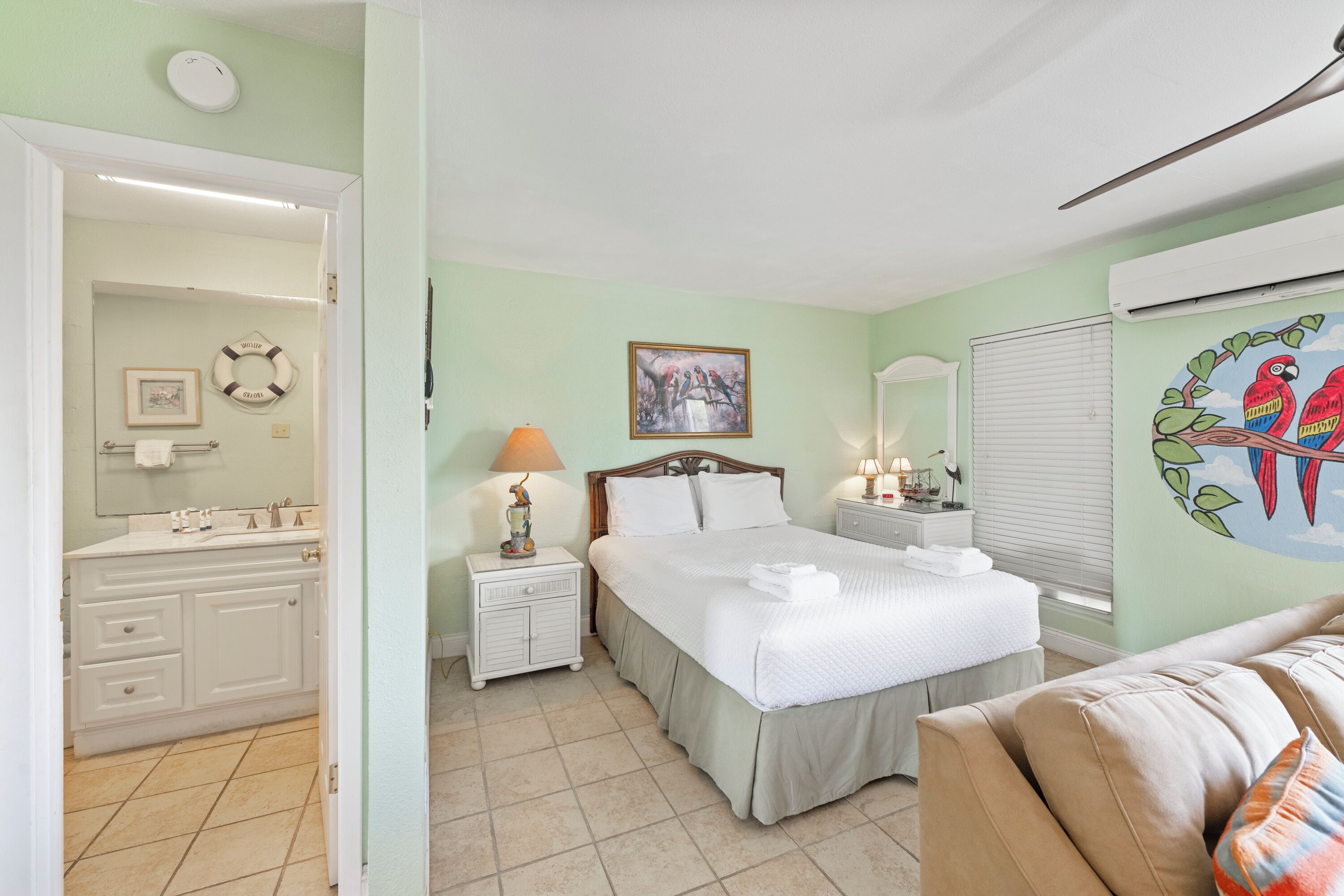 A bedroom with a bed, nightstands, a dresser, a mirror, and a wall with a painting.