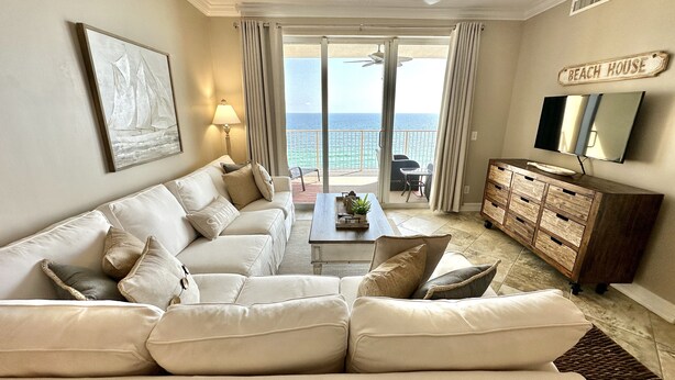 Ein Wohnzimmer mit einer Couch, einem Couchtisch und einem Fernseher. An der Wand befindet sich ein Schild mit der Aufschrift 'Beach House'.