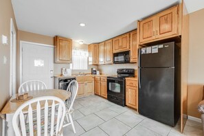 A kitchen with wooden cabinets, a black refrigerator, a microwave, and a stove.