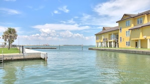 A waterfront property with a dock, a yellow building with balconies, and a clear view of the water. - Spacious studio condo with the best amenities in Port Aransas!  Community pool, (Port Aransas)