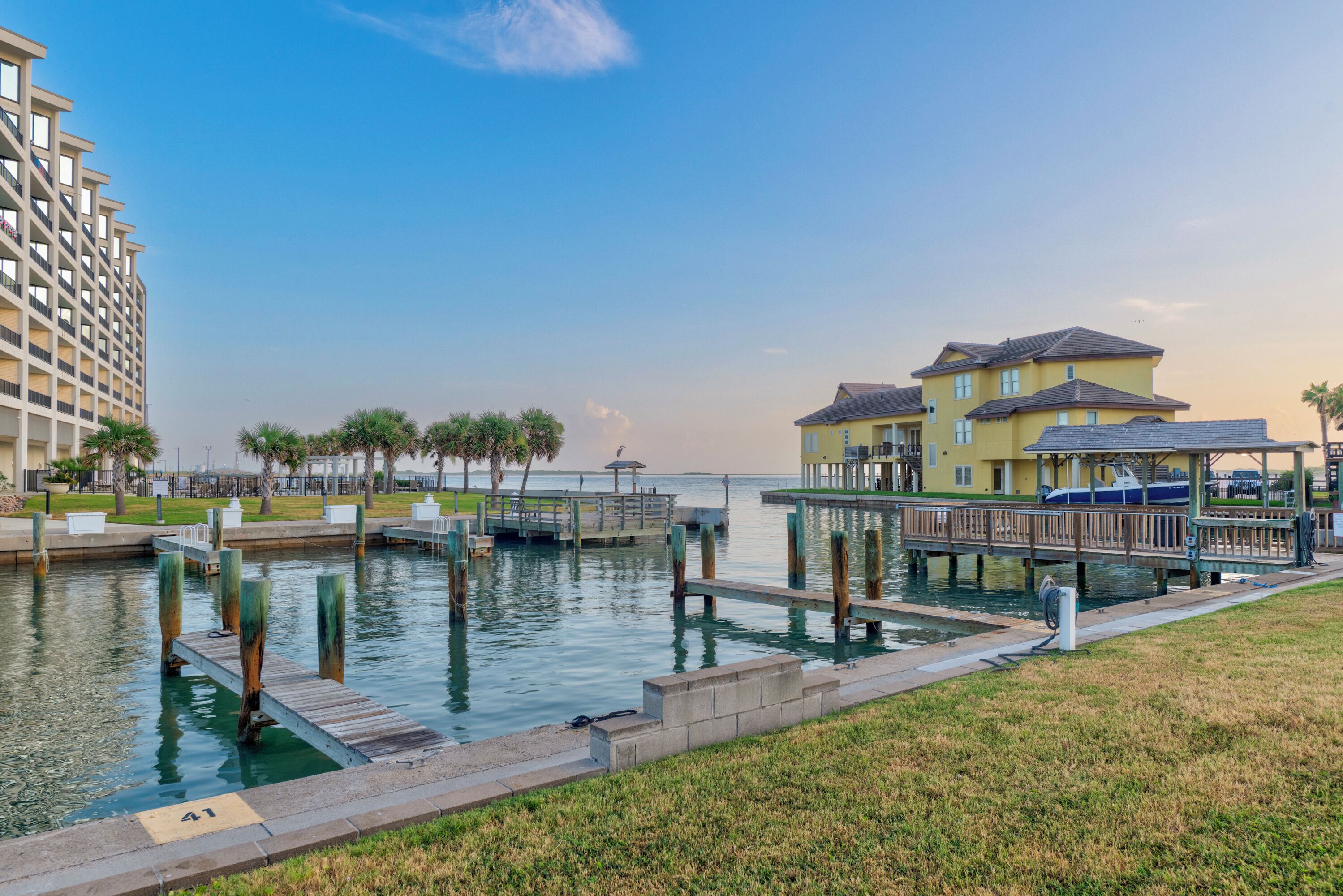 A waterfront property with a dock, a building with a yellow facade, and a high-rise building in the background.